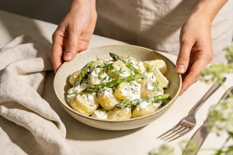 Krämig potatissallad med sparris och citron, serverad i skål som vårigt tillbehör till buffé och catering.