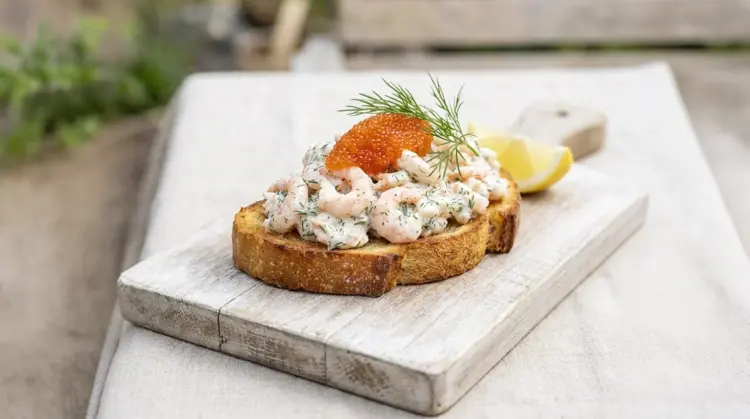 Toast skagen står utomhus på ett sommarbord. Rätten är lagad utifrån Catering by Nordrests toast skagen recept.